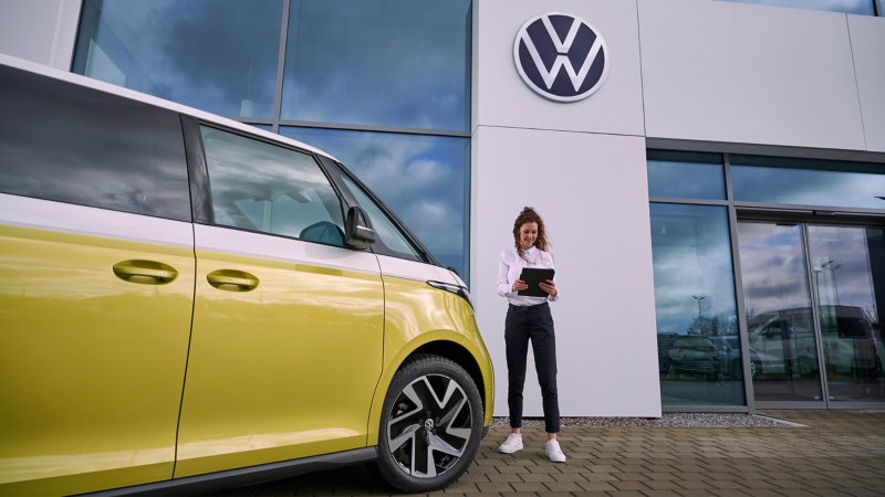 Mujer del servicio técnico para eléctricos de VW al lado del ID. Buzz.