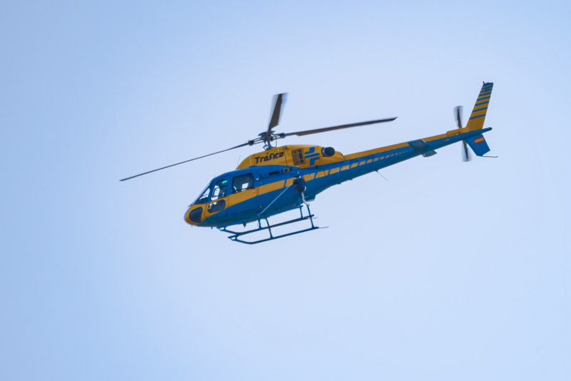 Helicóptero de la DGT azul y amarillo sobrevolando un cielo azul