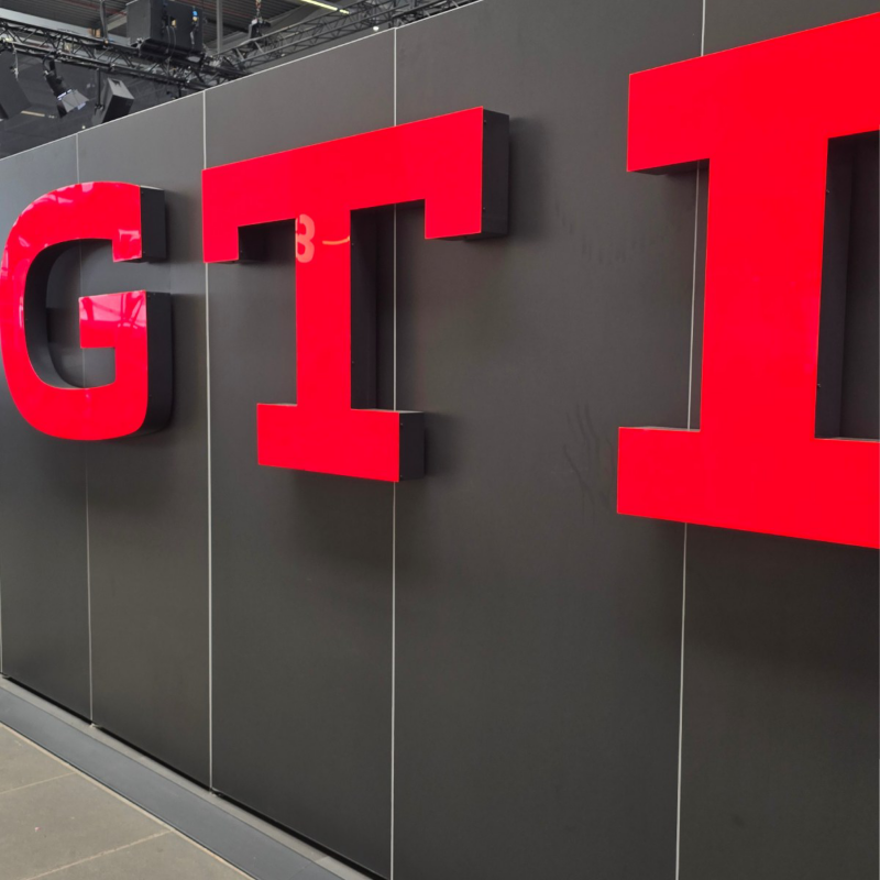 Letras grandes de color rojo con las siglas GTI de Volkswagen sobre pared oscura.