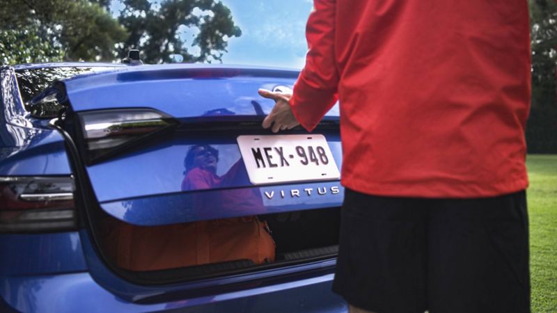 Hombre abre cajuela de un auto sedán Virtus 2024. 