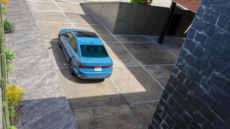 Jetta 2025, versión Highline en color exterior azul, sale de la cochera de una casa moderna. 