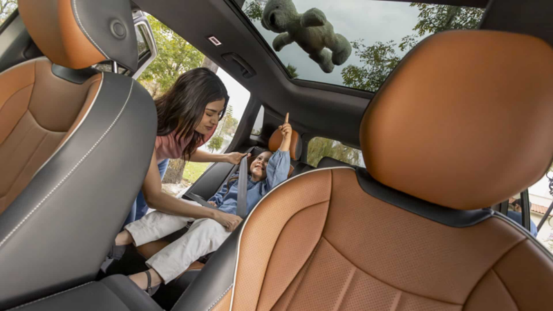 Mujer pone cinturón de seguridad a niña sentada en segunda fila dentro de Tiguan 2025.