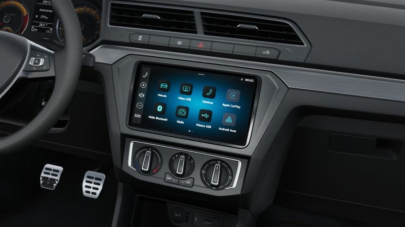 Interior del Volkswagen Saveiro mostrando la consola central con pantalla táctil, controles de clima y volante moderno.