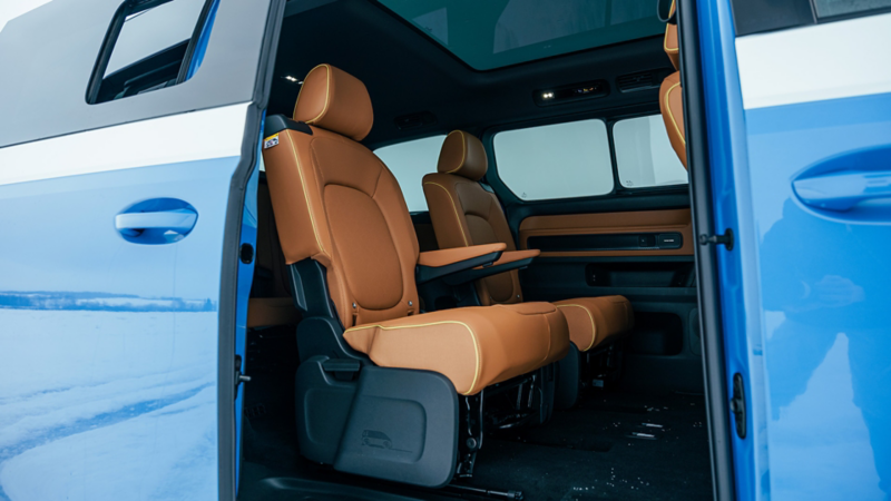 L'intérieur spacieux du Volkswagen ID. Buzz 2025 avec sièges spacieux, toit panoramique et portes coulissantes ouvertes avec la pédale virtuelle "Easy Open". 