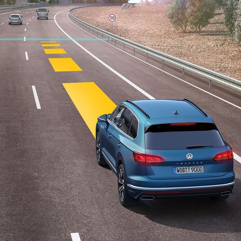 a blue Volkswagen model driving on a main road with a yellow line to demonstrate autonomous driving functionality 