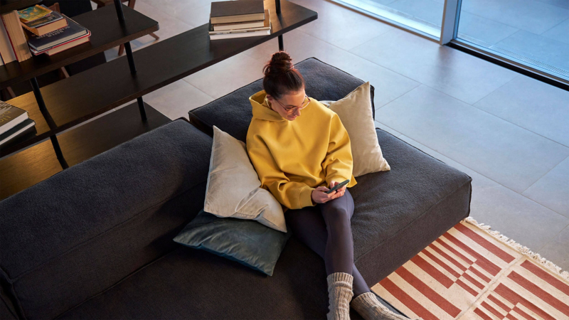 A young woman checks her smartphone on a sofa