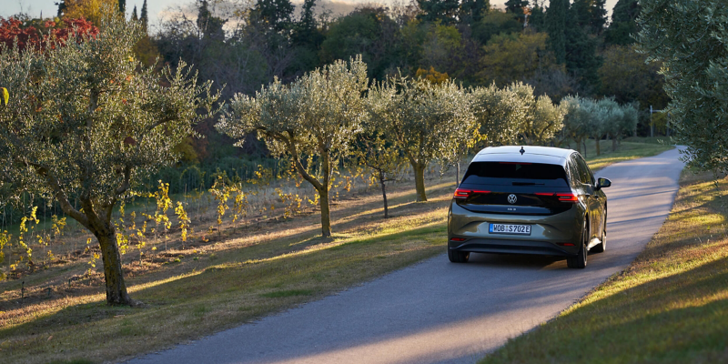 A VW driving through a country lane surrounded by trees