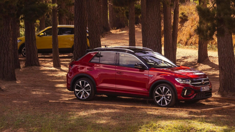 A short description of a red Volkswagen T-Roc car parked in a forest, promoting PCP offers.