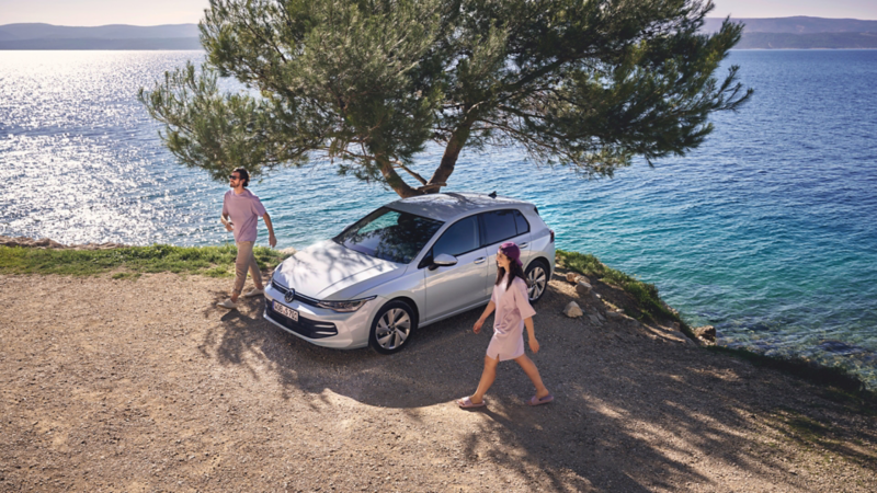 En mand og kvinde går ved en golf parkeret ved vandet