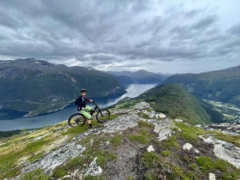 Sophie med cykel på toppen av ett berg.