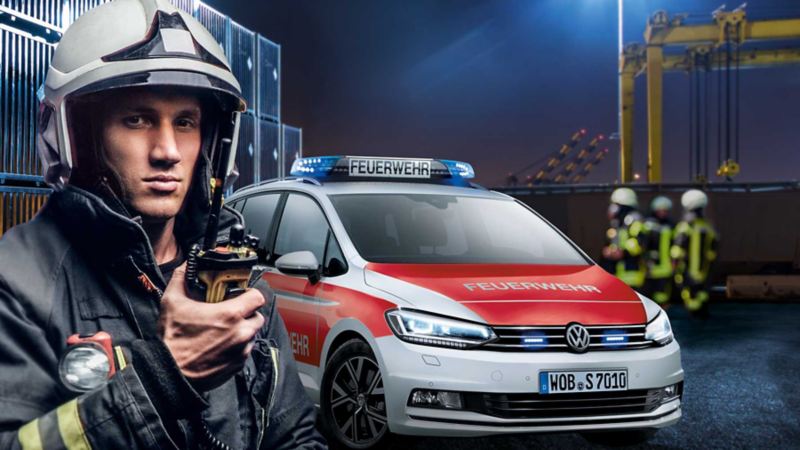 Ein Feuerwehrmann am Einsatzort, im Hintergrund ein Feuerwehrauto von Volkswagen