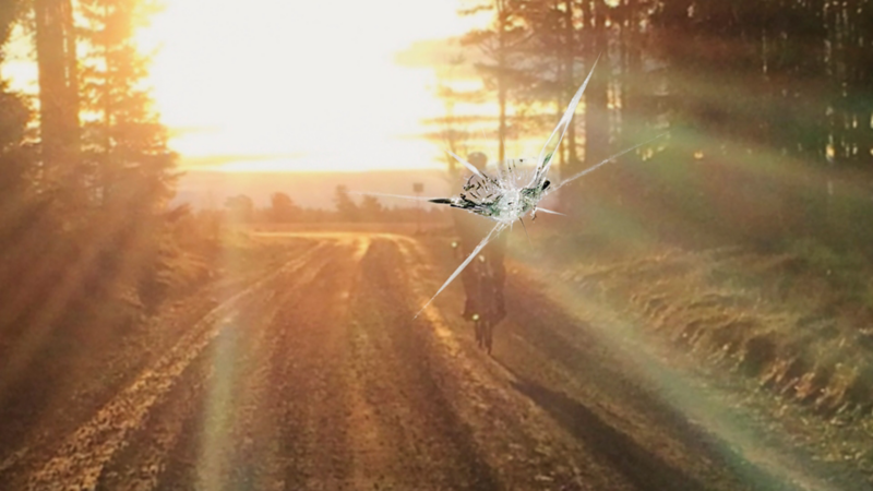  Detalbild på ett stenskott i vindrutan på en bil. Solnedgång i bakgrunden
