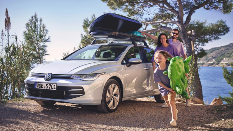  Family next to parked VW Golf, lake landscape in background