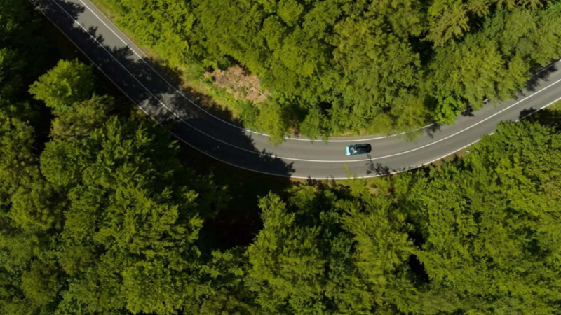 an aeriel shot of an ID. Buzz driving through a lush green countryside
