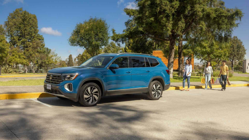 Volkswagen Teramont de color azul para 6 pasajeros, estacionada con personas caminando a un lado.