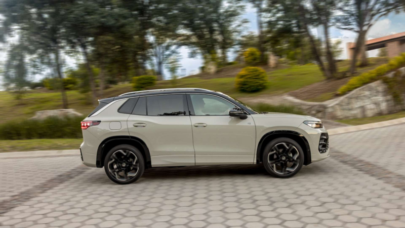Nuevo Tiguan color beige circula en carretera adoquinada y rodeada por jardines.