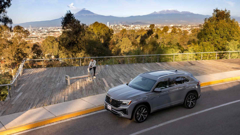 Volkswagen Cross Sport de color gris, estacionado en mirador con vista a la ciudad y los volcanes.