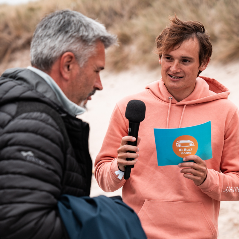 Während einer Aufgabe befragt Niclas Nebelung einen Mann am Strand zum ID. Buzz.