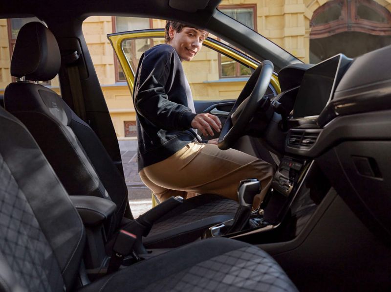 A man getting into a yellow T-Cross