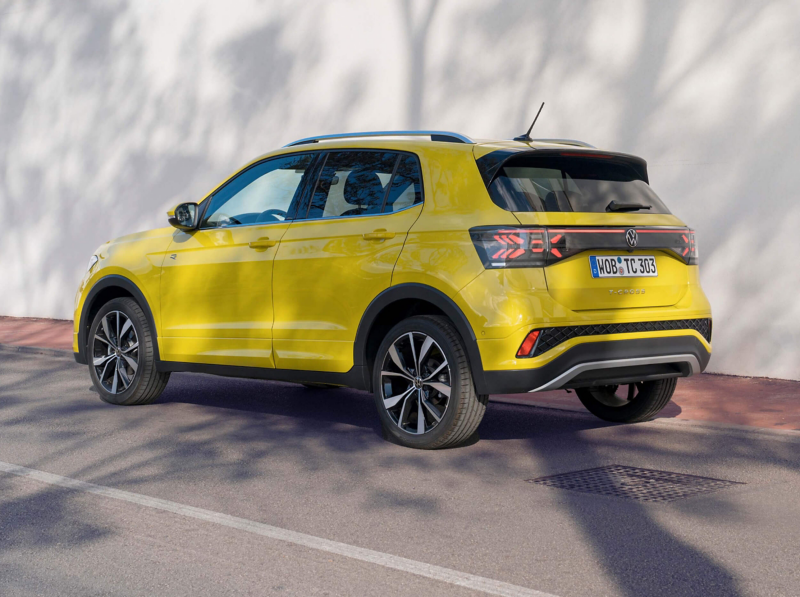 A side view of a yellow T-Cross parked against a white wall