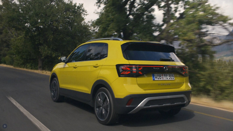 Volkswagen T-Cross amarillo visto desde atrás en una carretera de montaña.