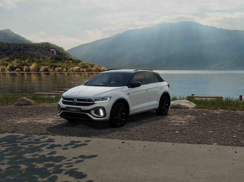A white VW T-Roc Black Edition against a lake with a mountain in the background