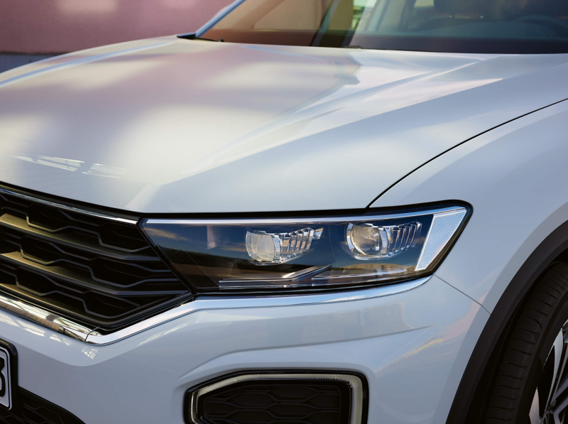A close-up of a headlight of a white VW T-Roc
