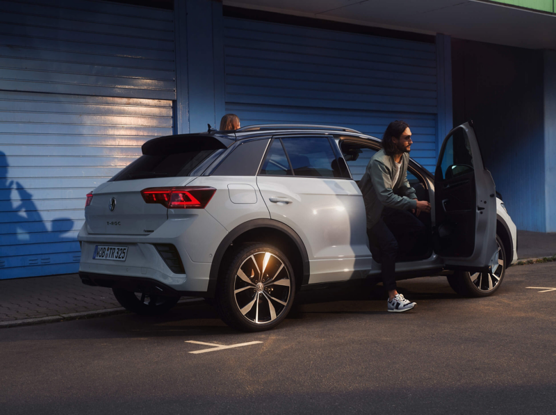 A man getting out of a white VW T-Roc at night