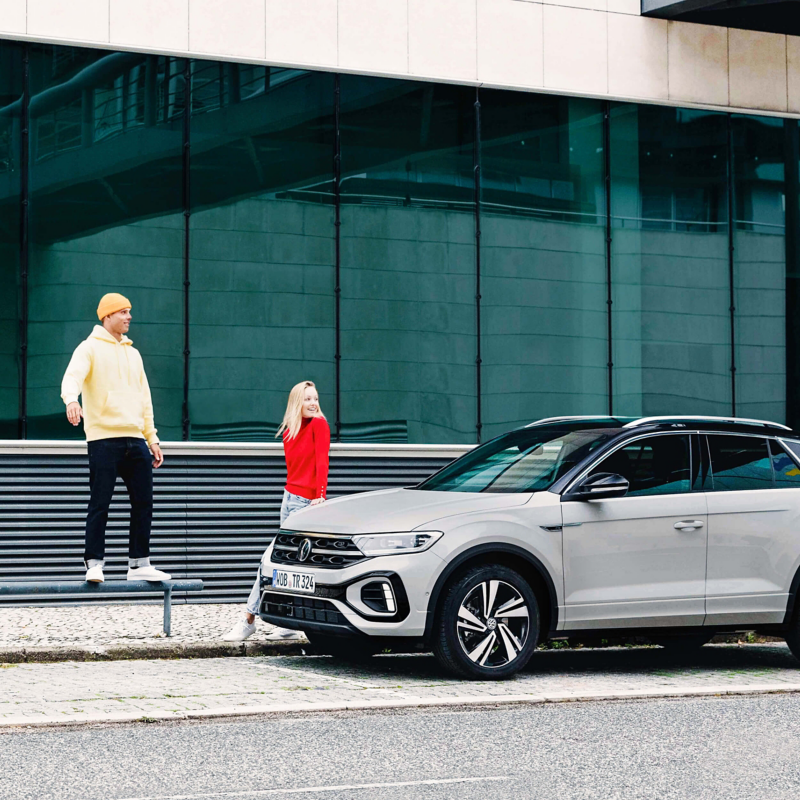 A man and a girl standing next to a white VW T-Roc