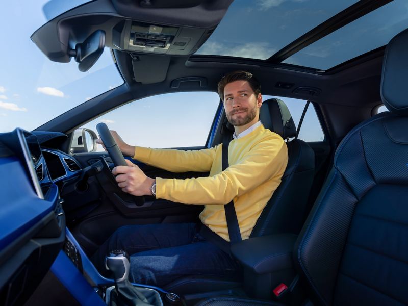 Man on the driving seat holding steering wheel.