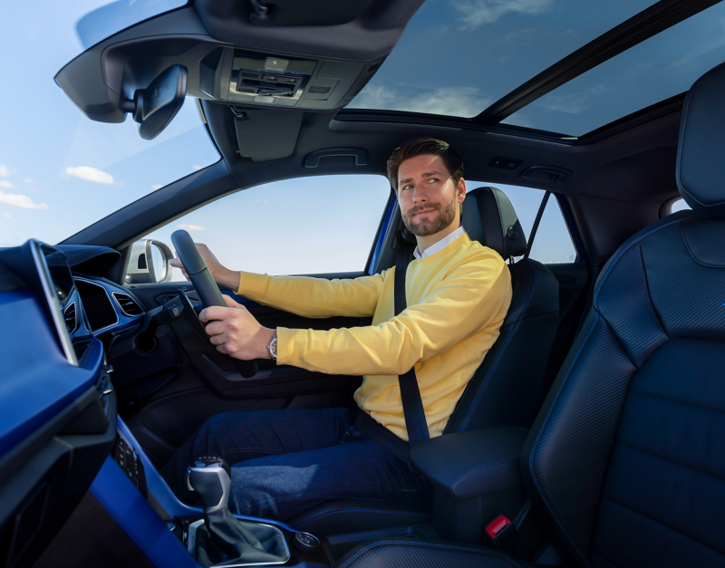 Man on the driving seat holding steering wheel.