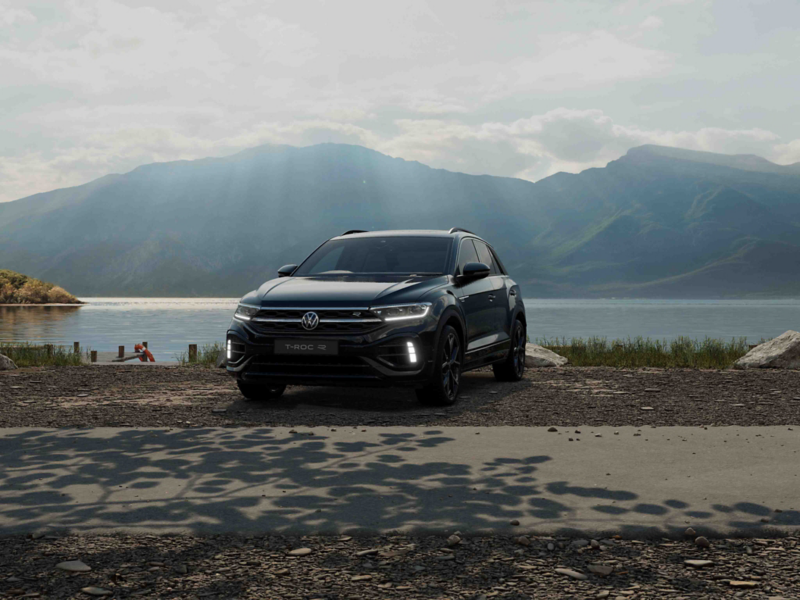 A grey VW T-Roc with a lake and a mountain in the background