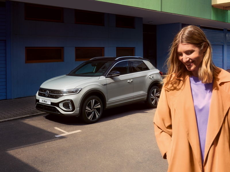 New blue T-Roc parked in town. A woman walking in front of the car