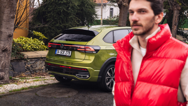 A man walking past a parked VW Taigo. 