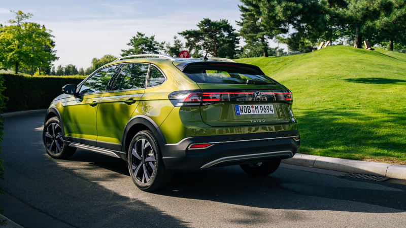 A VW Taigo driving past a wooded area. 