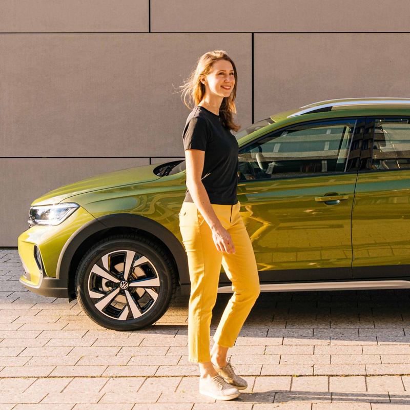 A smiling woman standing next to a VW Taigo. 
