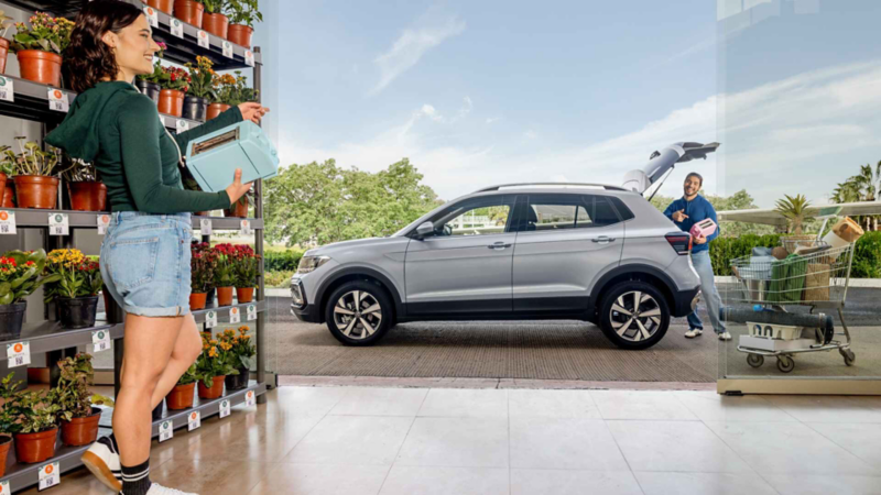 Mujer carga tostador hacia cajuela de Volkswagen Taigun de color gris.