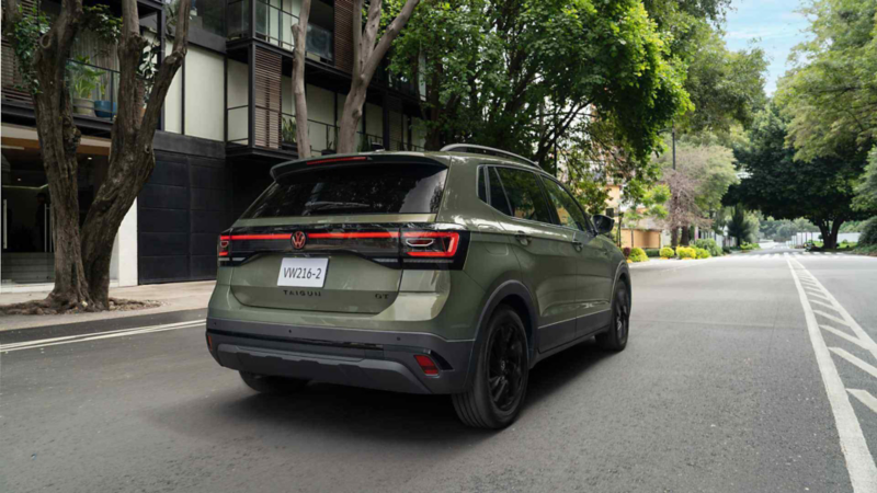 Vista trasera de un Volkswagen Taigun verde estacionado en una calle residencial.