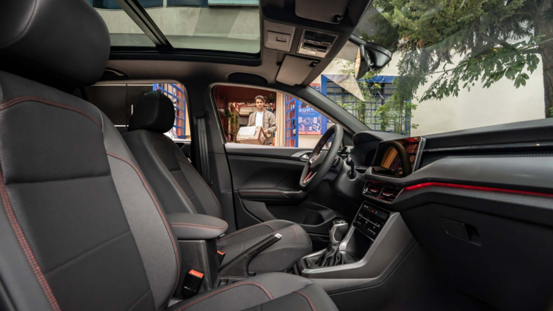 Interior negro de Volkswagen Taigun con detalles rojos y techo panorámico, visto desde atrás.