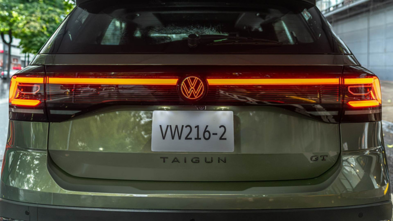 Vista trasera de un Volkswagen Taigun verde con las luces posteriores encendidas.