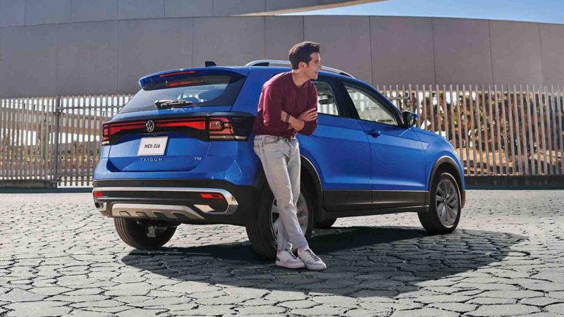 Conductor de Taigun 2023 se recarga en SUV compacto de color azul.