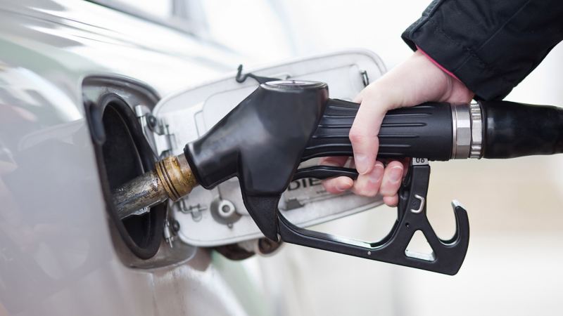 Ein Tankrüssel wird von einer Hand in den Tankstutzen eines Autos geführt.