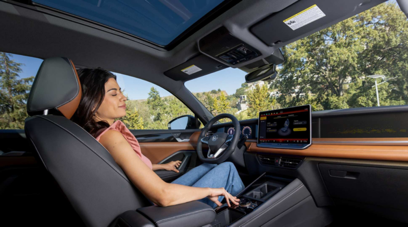 Conductora relaja asiento delantero en interior de Volkswagen Tiguan con pantalla touch.
