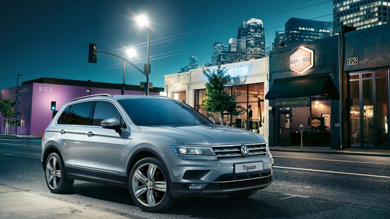 A VW Tiguan driving down a street at night