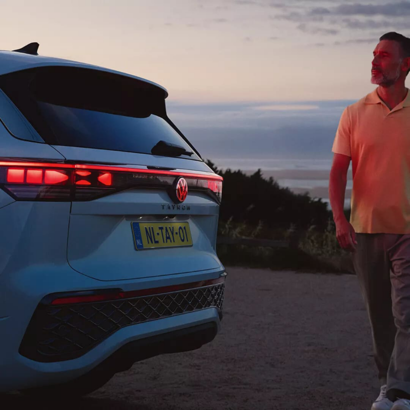 Witte Tayron R-Line met lampen aan en een man die achterlangs loopt