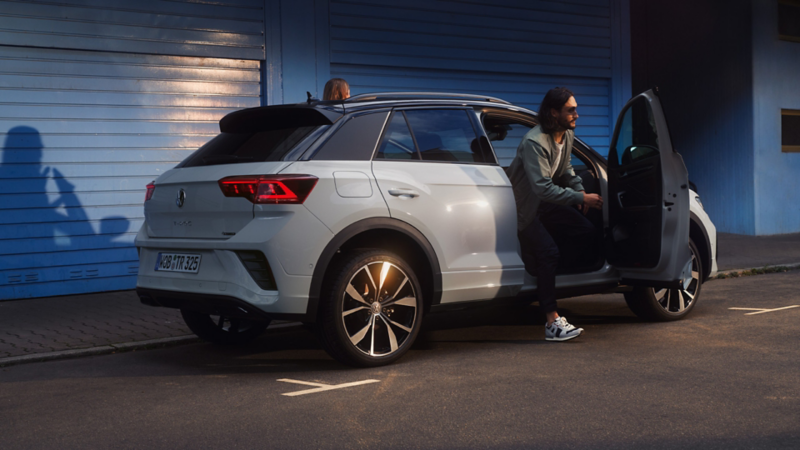 Ein weißer VW T-Roc aus dem zwei Personen aussteigen.