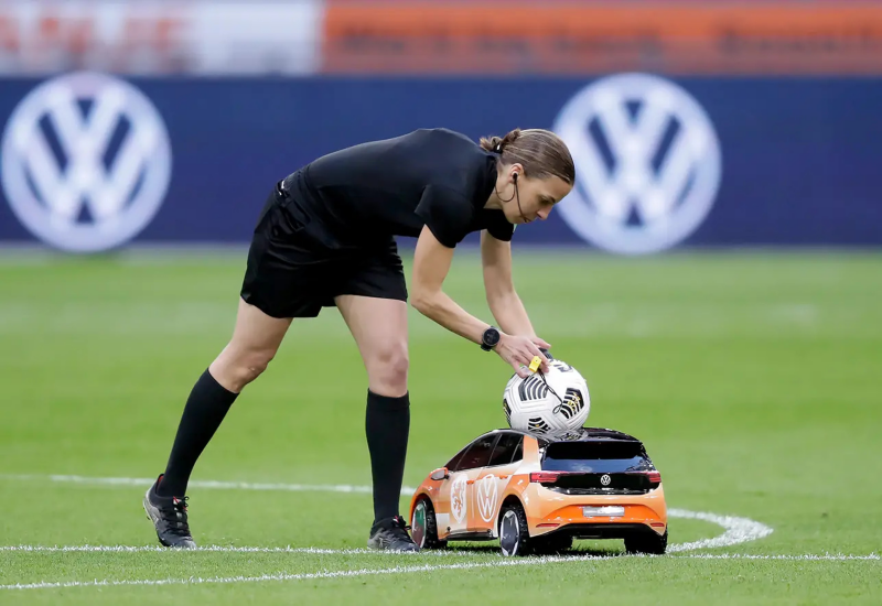 Vrouwelijke scheidsrechter pakt de bal van een kleine bestuurbare ID.3 op een voetbalveld