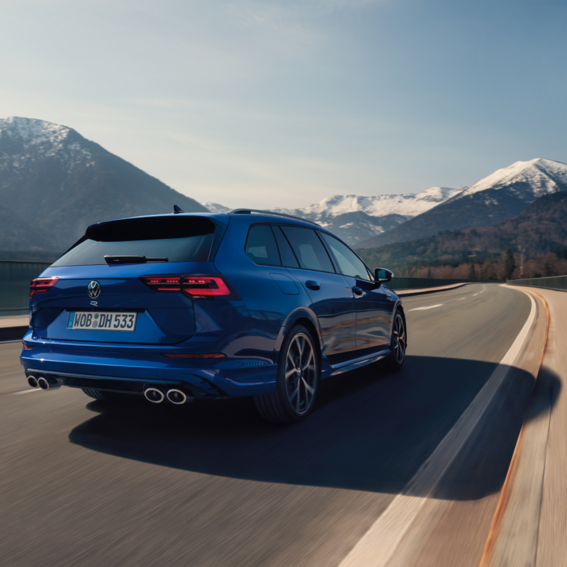 Volkswagen Golf Variant R azul circulando por una carretera con unas montañas nevadas de fondo