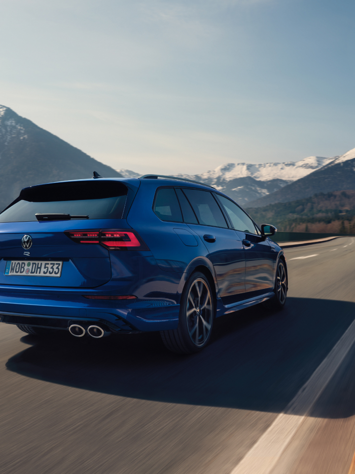 Volkswagen Golf Variant R azul circulando por una carretera con unas montañas nevadas de fondo