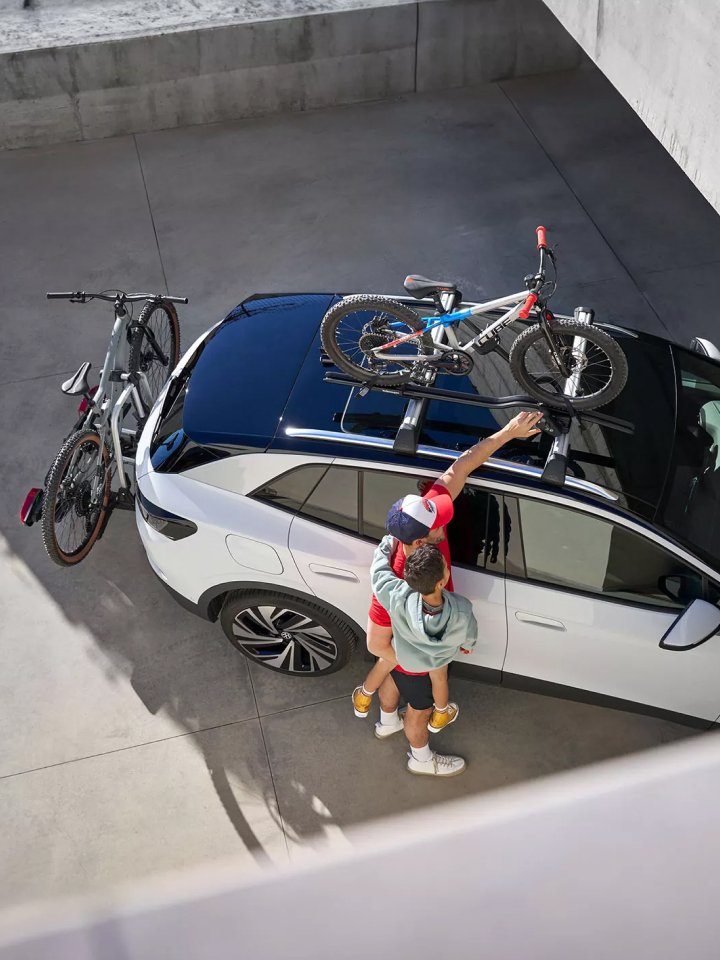 Un padre con su hijo montando unas bicicletas en lo alto de un Volkswgen